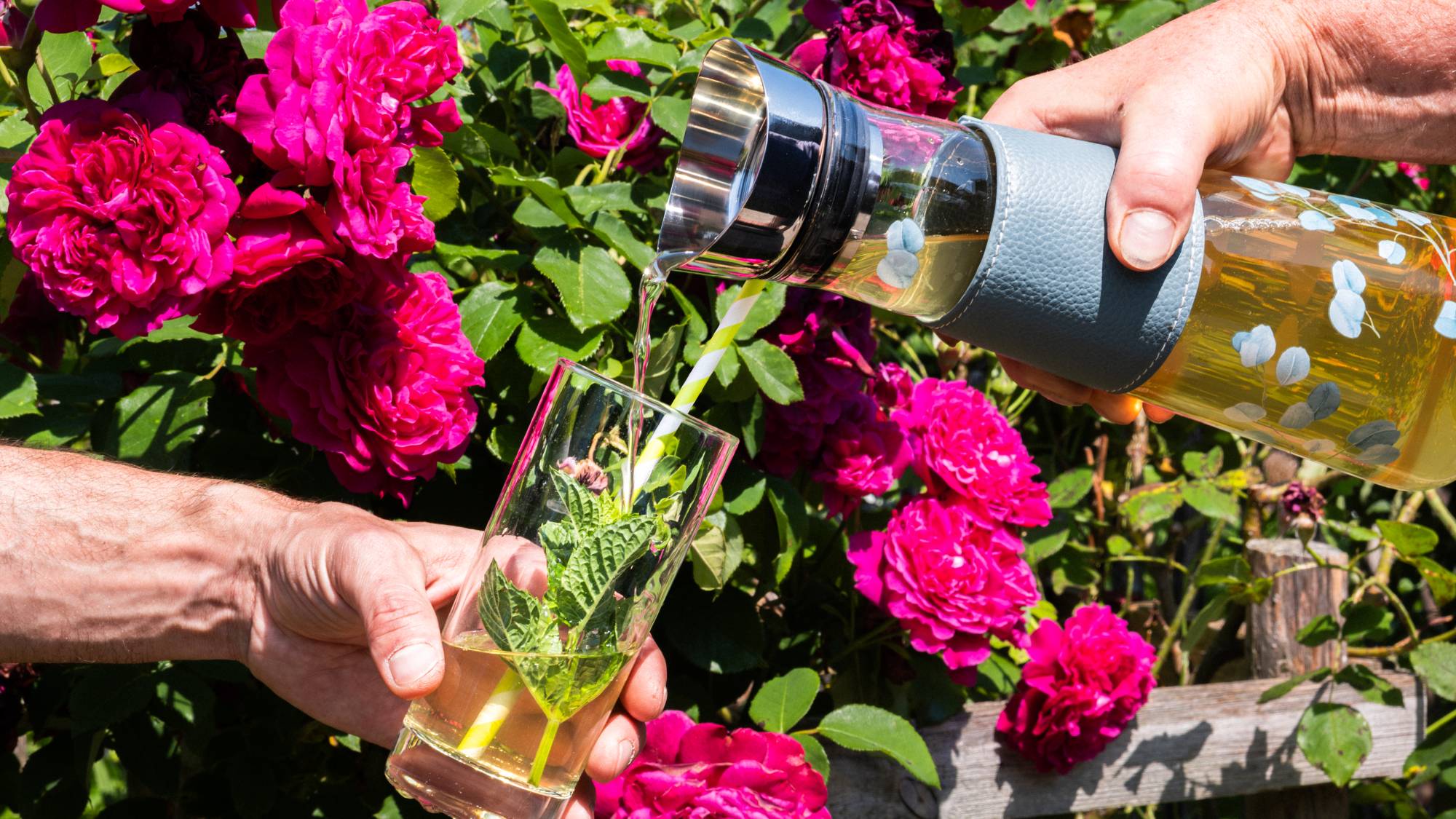Du thé froid versé dans un verre, dans un décor avec des fleurs.